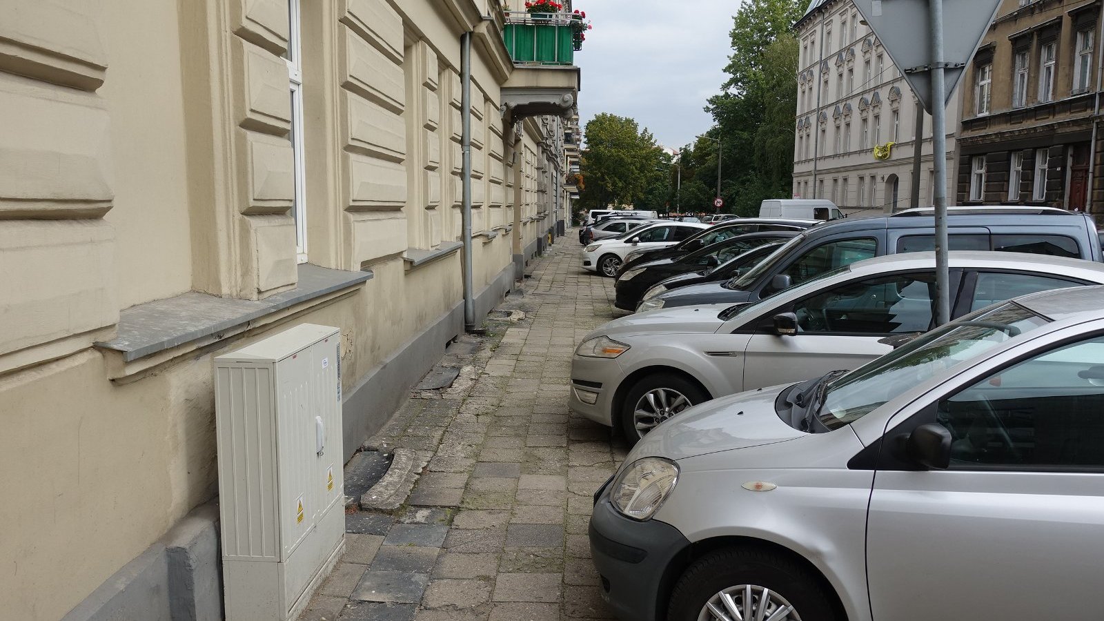 Na zdjęciu ulica, której chodnik jest niemal całkowicie zastawiony samochodami