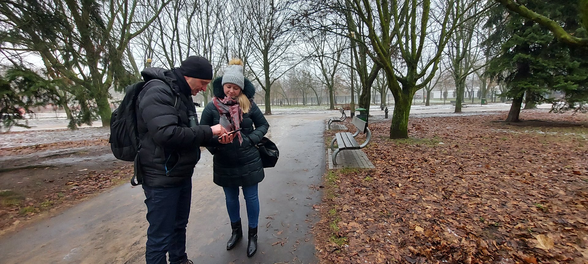 Zdjęcie przedstawia pracowników Zarządu Zieleni Miejskiej - mężczyznę i kobietę - w parku. - grafika rozmowy