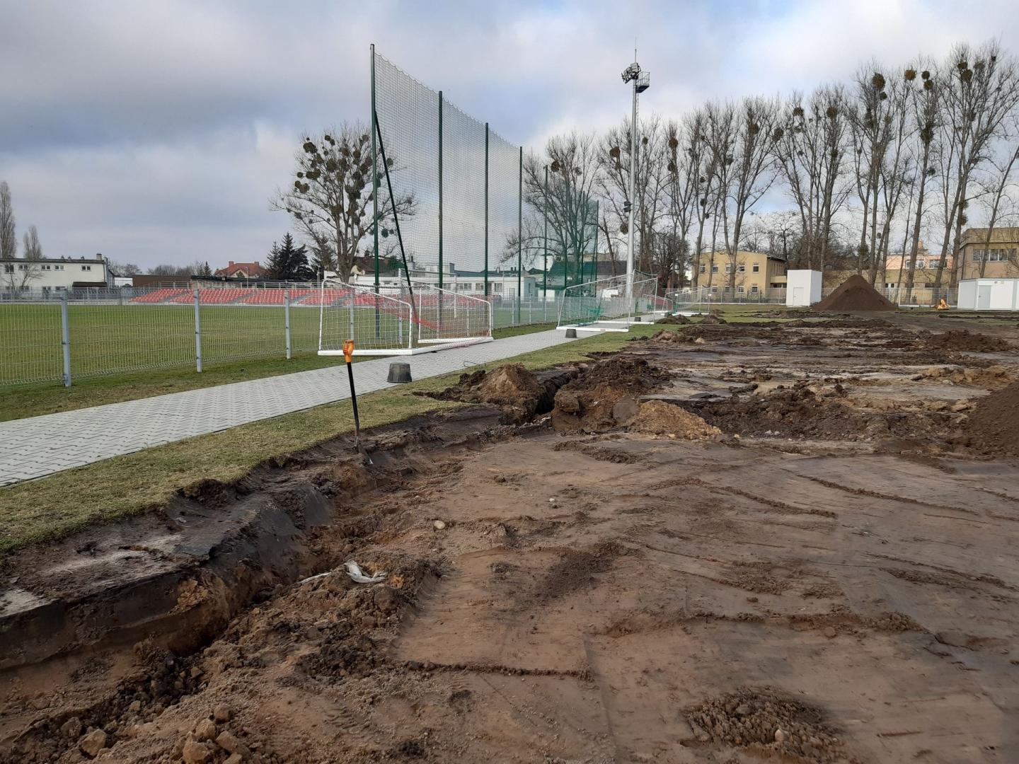 Galeria zdjęć przedstawia prace budowlane nad nowym boiskiem. Widać na nich hałdy ziemi, maszyny budowlane i pracowników. - grafika rozmowy