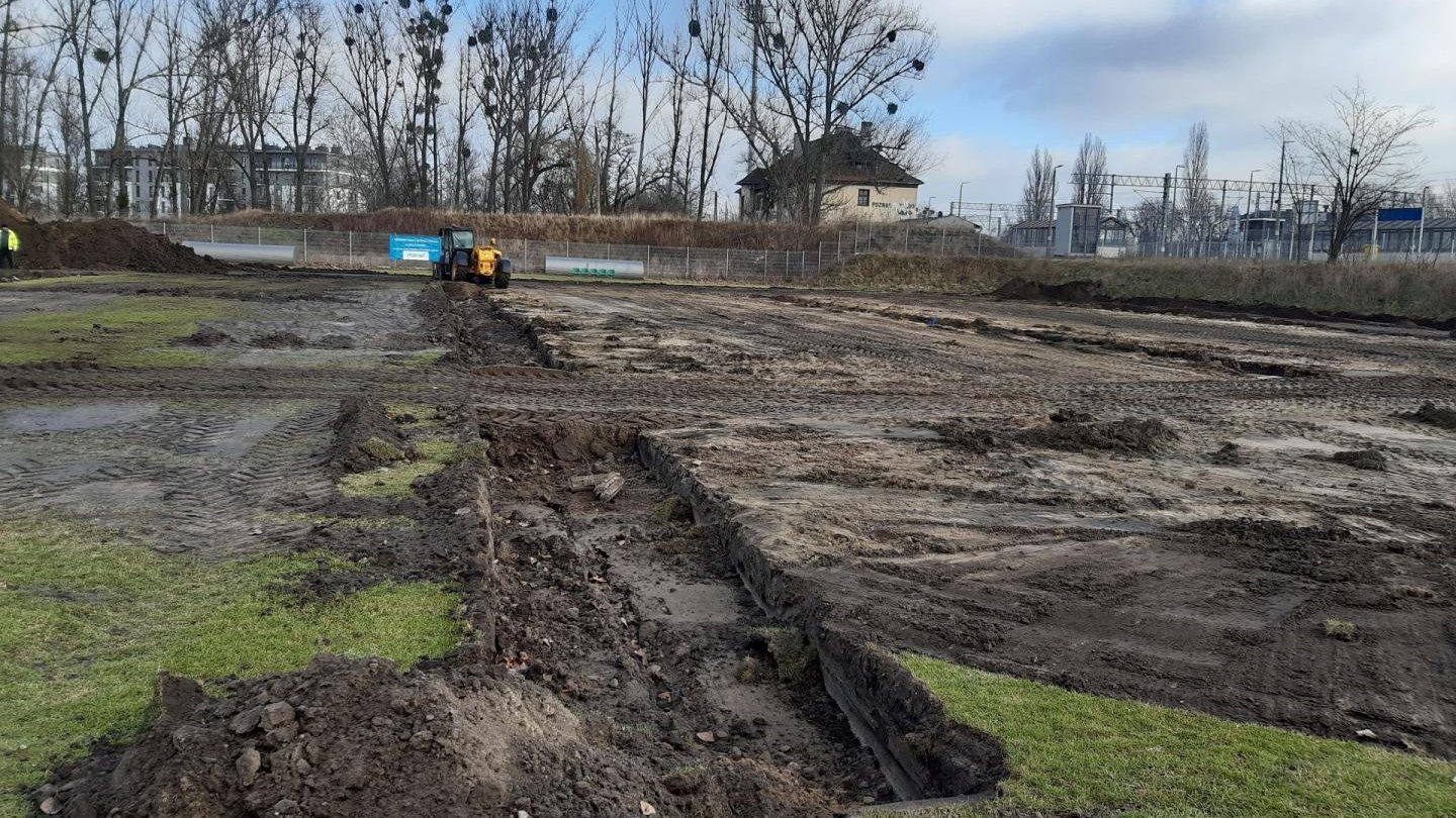 Galeria zdjęć przedstawia prace budowlane nad nowym boiskiem. Widać na nich hałdy ziemi, maszyny budowlane i pracowników.