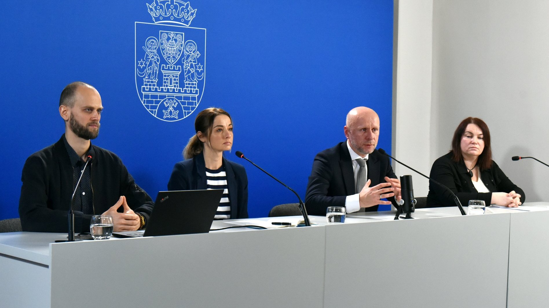 Galeria zdjęć przedstawia zdjęcia z konferencji prasowej. Widać na nich ludzi siedzących za stołem konferencyjnym.