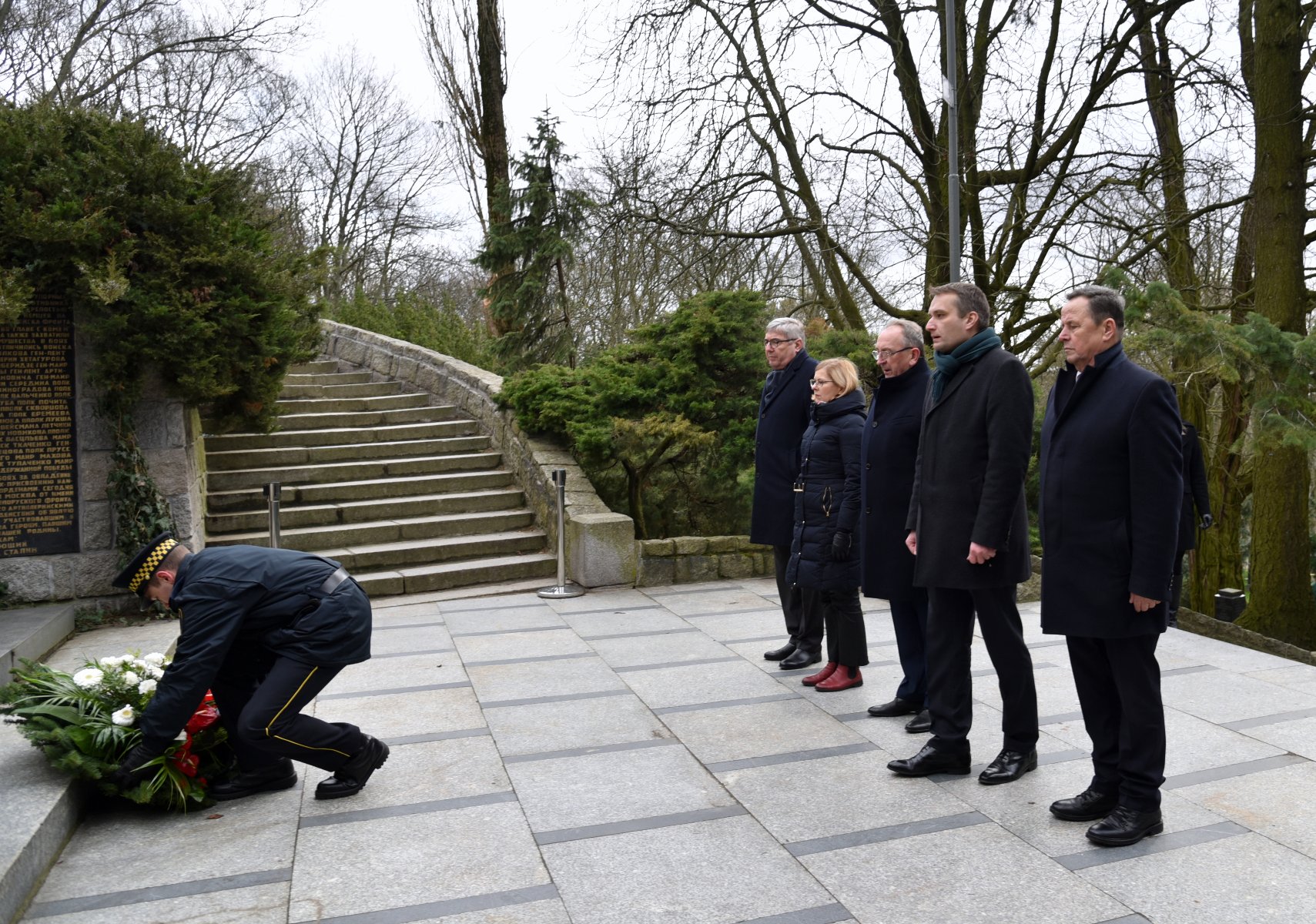 Galeria zdjęć przedstawia przedstawicieli Miasta Poznania składających kwiaty pod pomnikiem. - grafika rozmowy