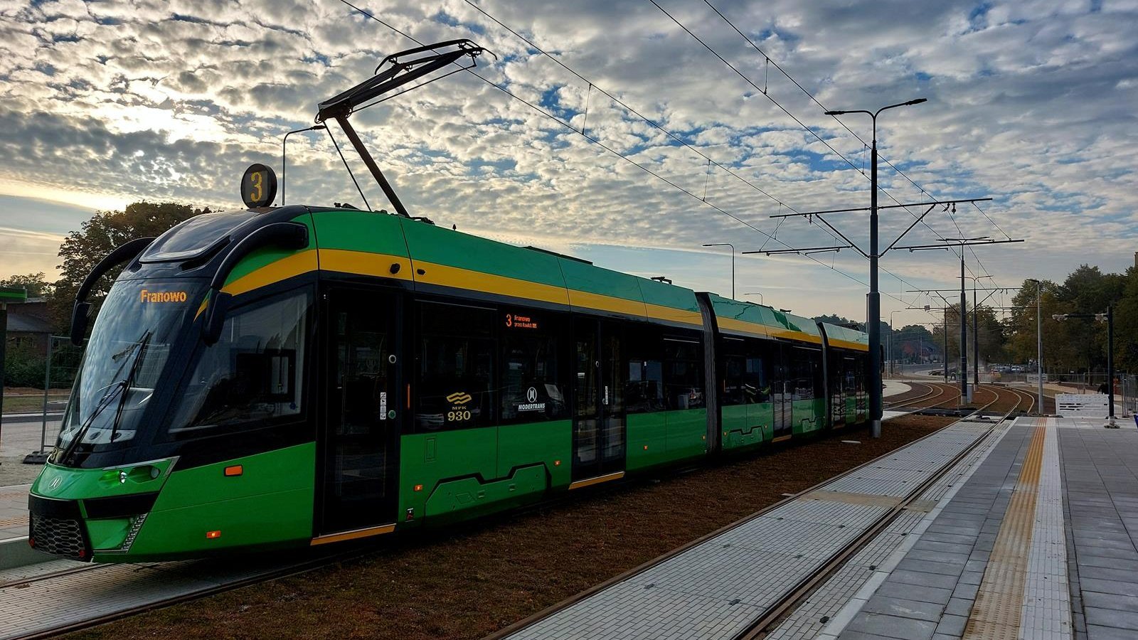 Na zdjęciu tramwaj na torowisku, nad nim niebo z białymi chmurami