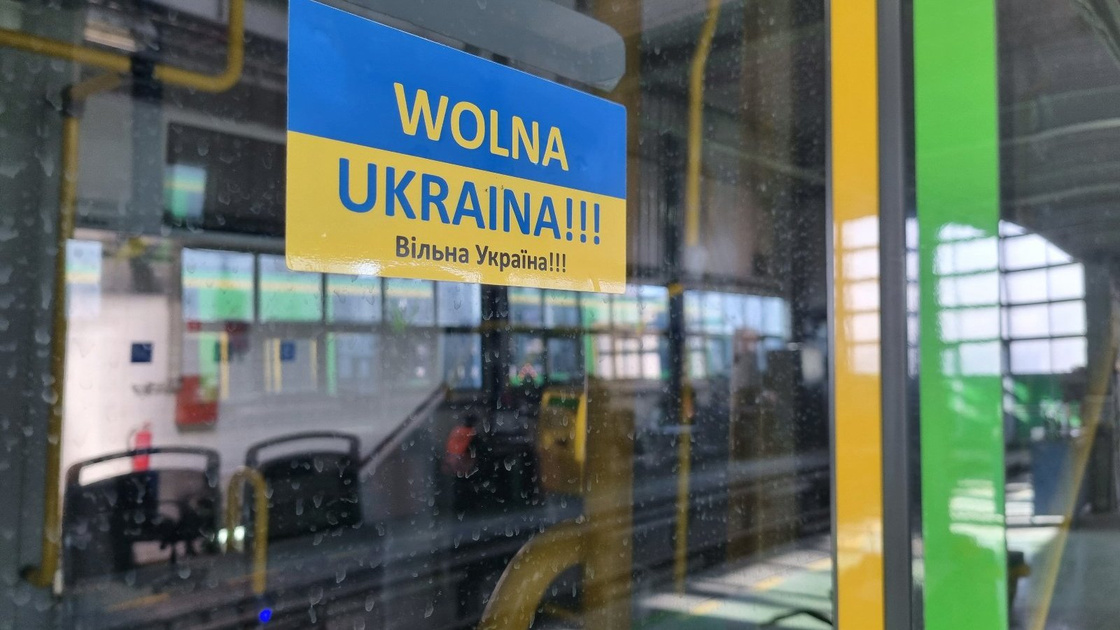 Niebiesko-żółta naklejka z napisem Wolna Ukraina po polsku i ukraińsku naklejona na drzwiach tramwaju