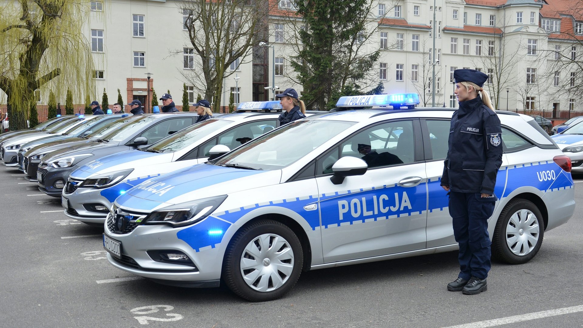 Na zdjęciu rząd policyjnych radiowozów - grafika rozmowy