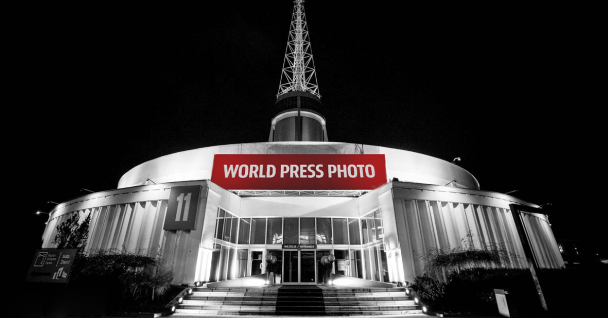 Grafika przedstawia zdjęcie budynku Iglicy MTP z napisem "World Press Foto". Fotografia jest czarno-biała, kolorowy jest tylko napis. - grafika rozmowy