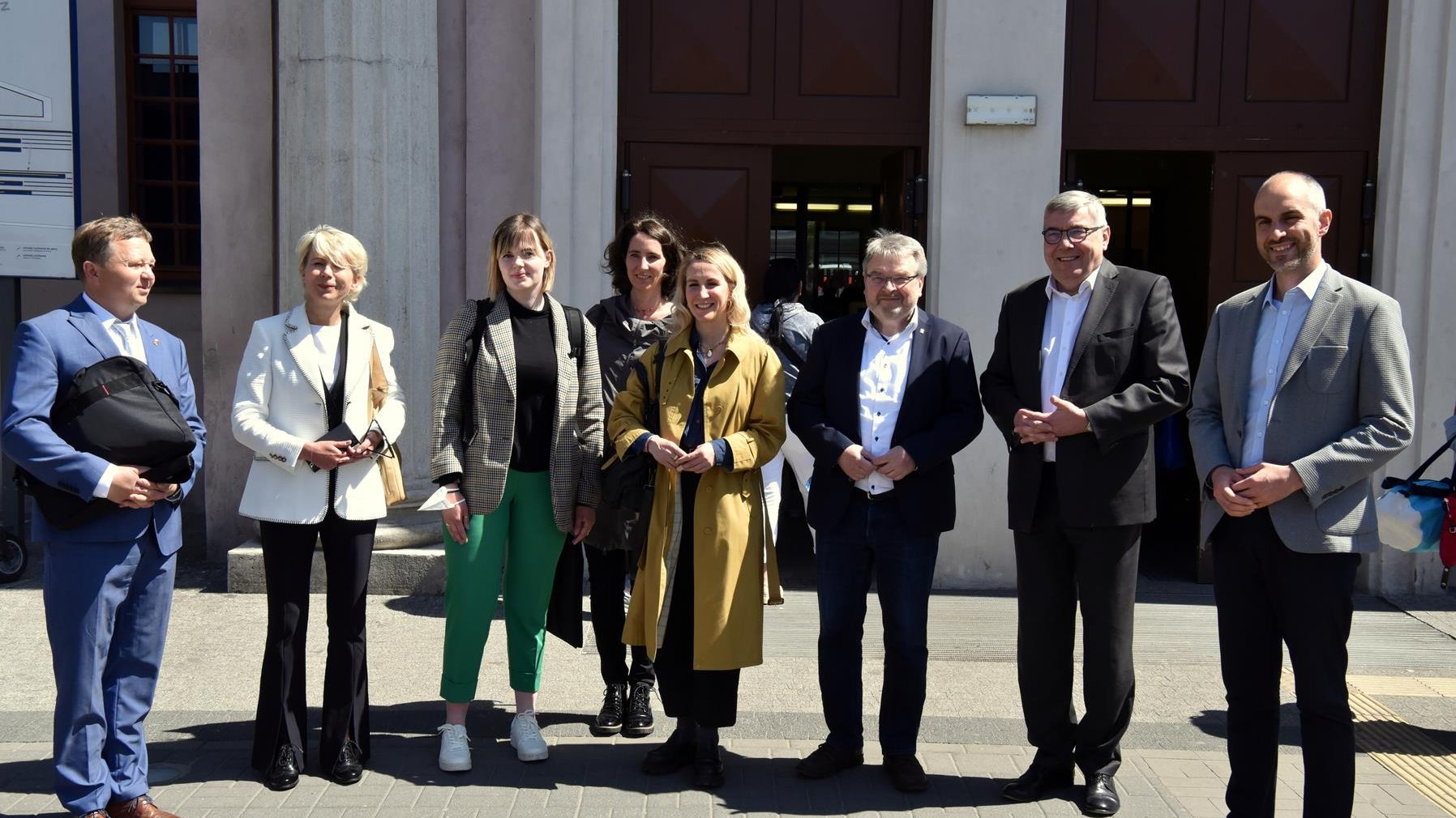 Na zdjęciu delegacja - grupa ludzi stojących obok siebie, za nimi budynek dworca