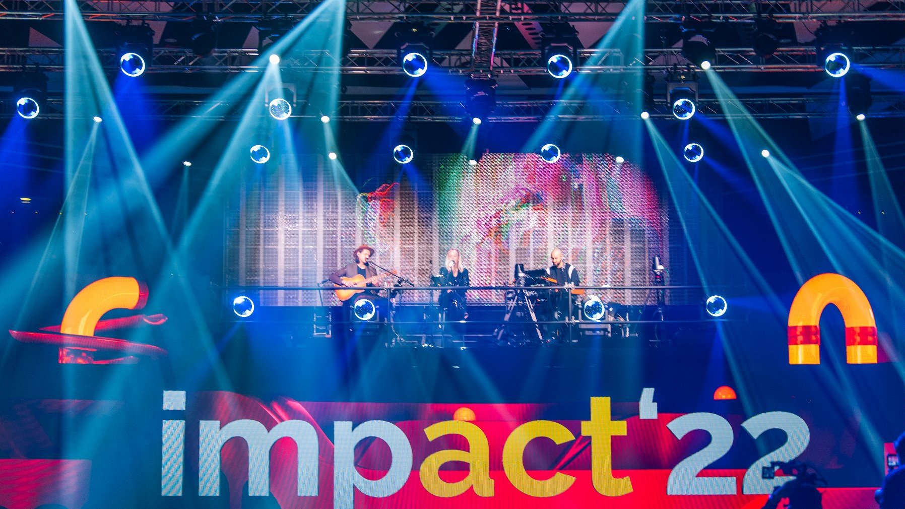 Na zdjęciu scena Impact'22 na niej zespół muzyczny, oświetlony wyraźnymi reflektorami