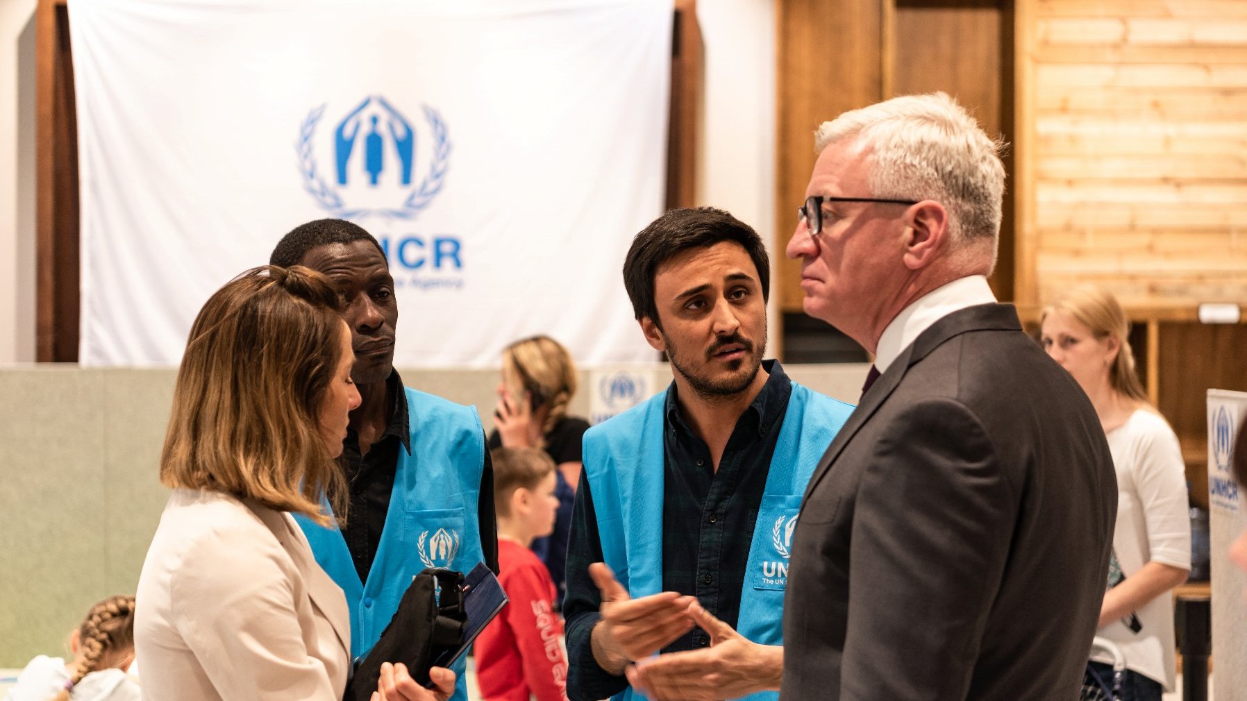 Na zdjęciu Jacek Jaśkowiak, prezydent Poznania, rozmawiający z pracownikami UNHCR, w tle logo placówki