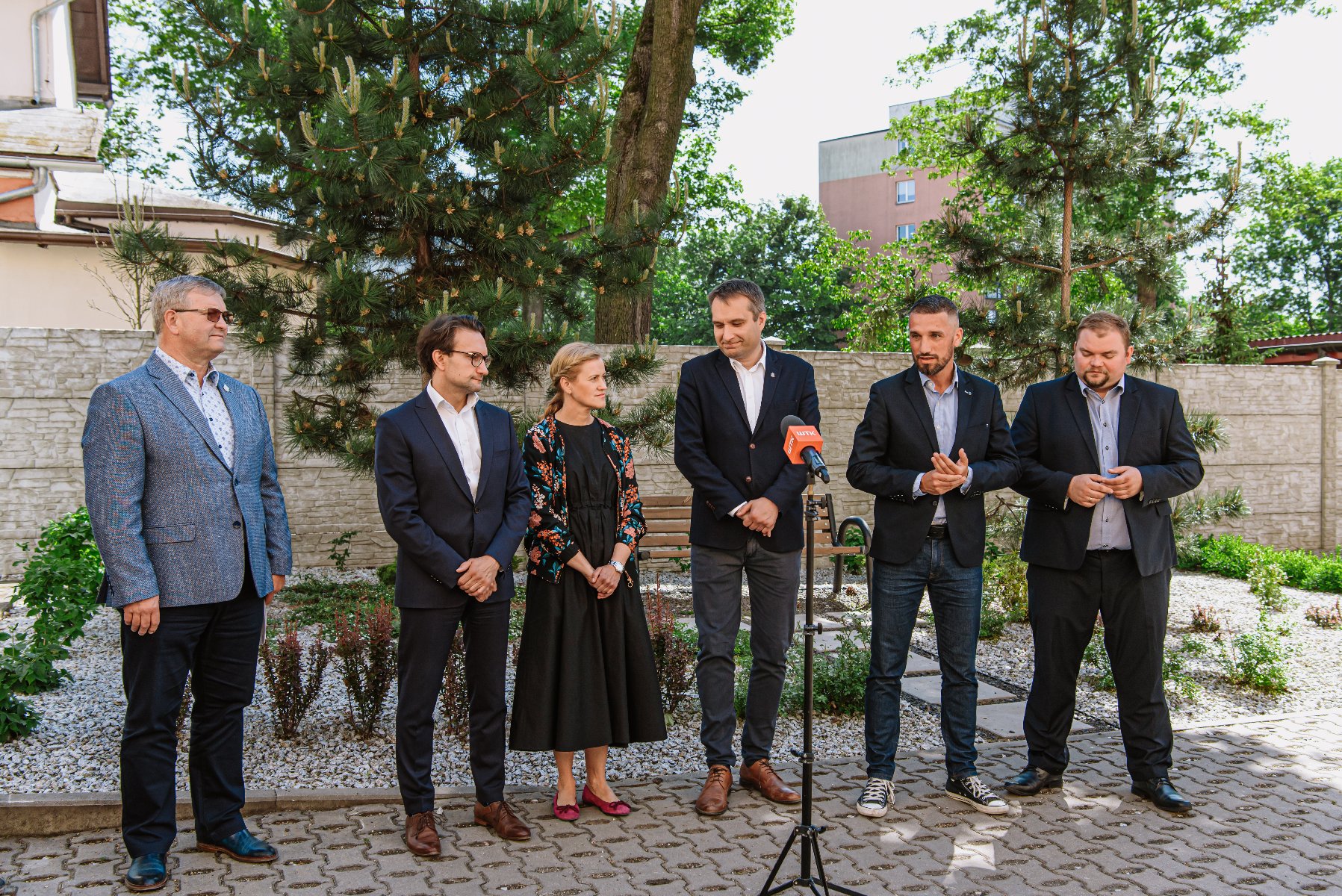 Galeria zdjęć przedstawia zdjęcie podwórka oraz osoby biorące udział w konferencji prasowej. - grafika rozmowy