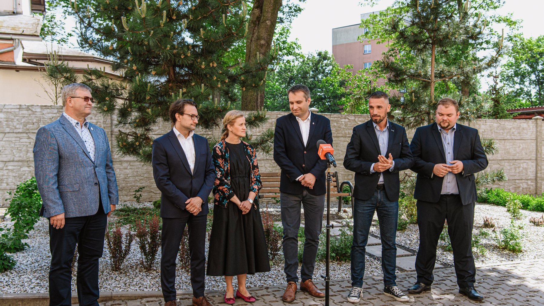 Galeria zdjęć przedstawia zdjęcie podwórka oraz osoby biorące udział w konferencji prasowej.