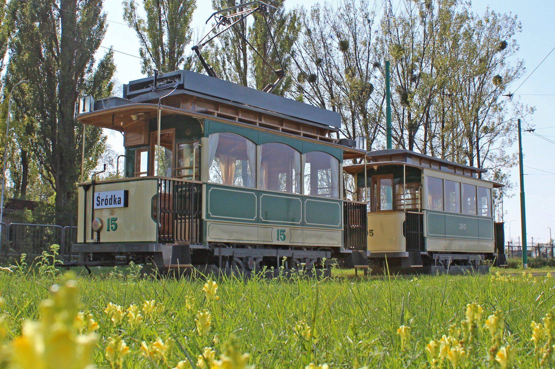 Na zdjęciu zabytkowy tramwaj stojący na torach, na pierwszym planie trawnik - grafika rozmowy