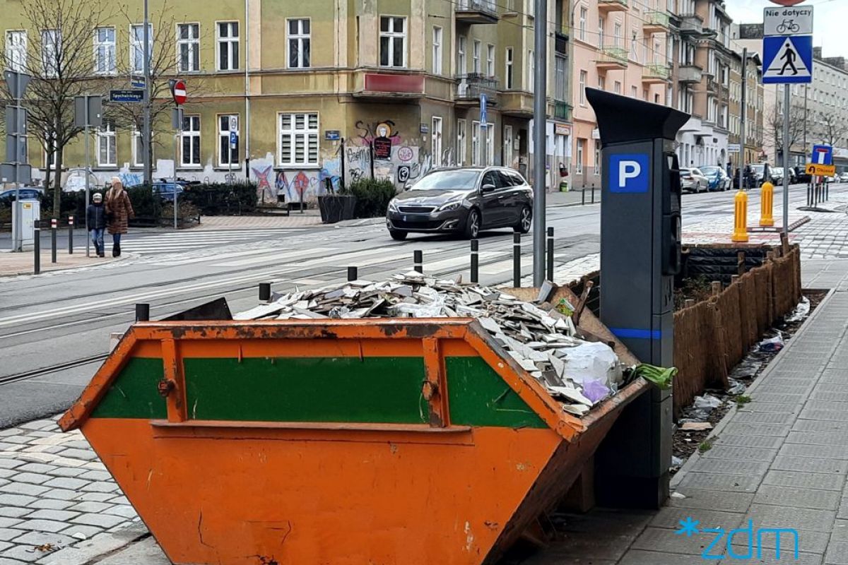 Zdjęcie przedstawia kontener na śmieci ustawiony na chodniku - grafika rozmowy