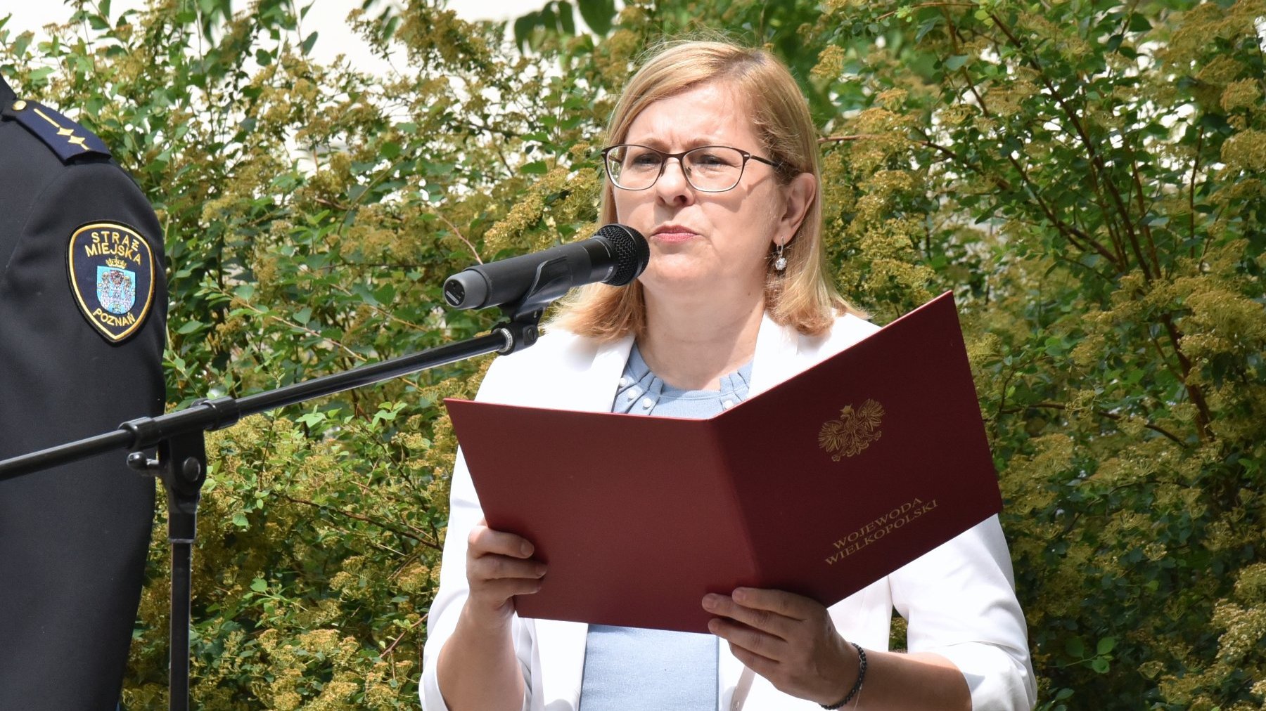 Na zdjęciu pełnomocniczka wojewody przy mikrofonie, w tle rośliny