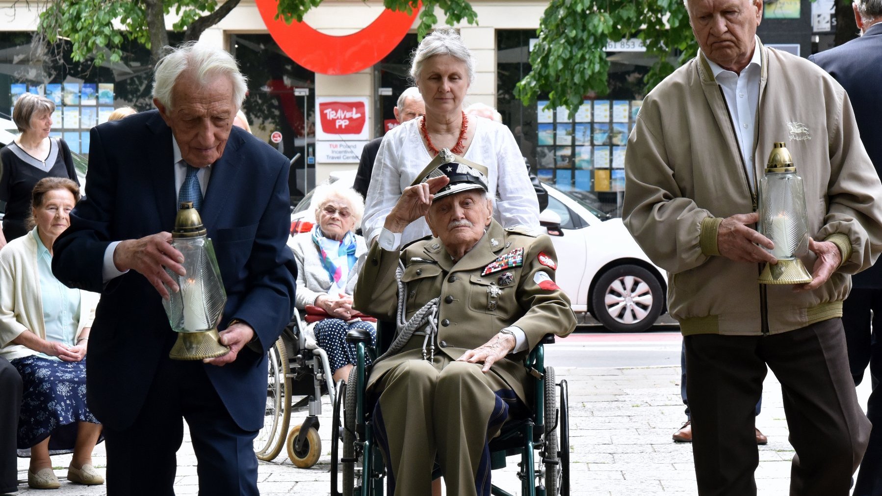 Na zdjęciu kombatanci składający znicze przed tablicą