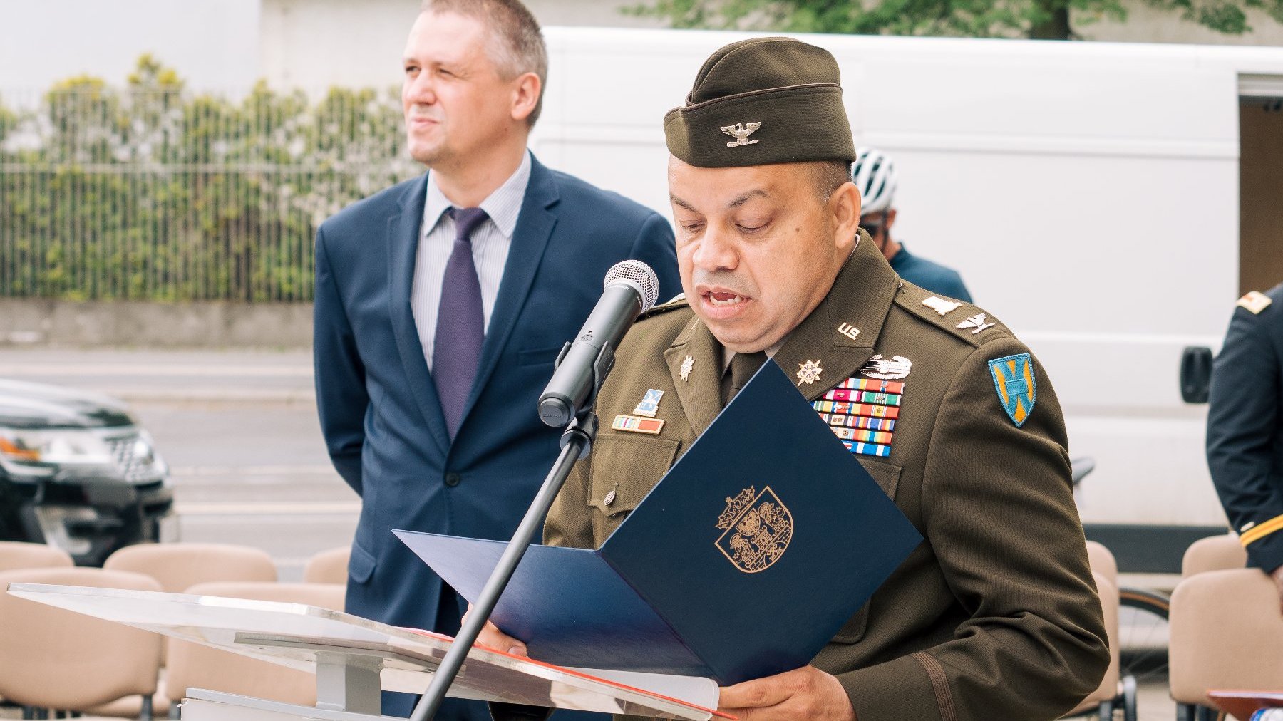 Na zdjęciu amerykański żołnierz przy mikrofonie, w tle dyrektor Gabinetu Prezydenta