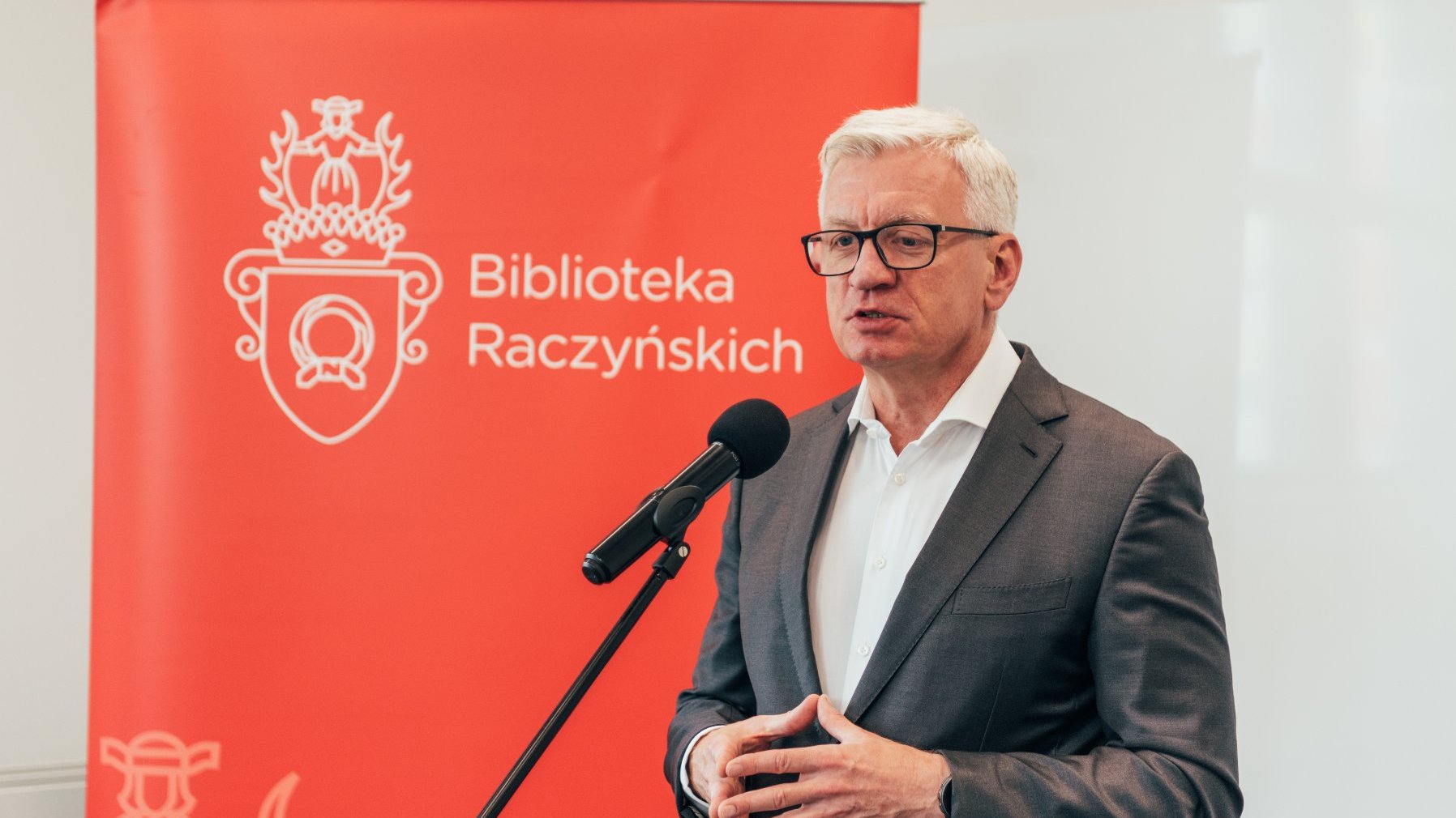 Na zdjęciu Jacek Jaśkowiak przy mikrofonie, w tle baner z napisem: Biblioteka Raczyńskich