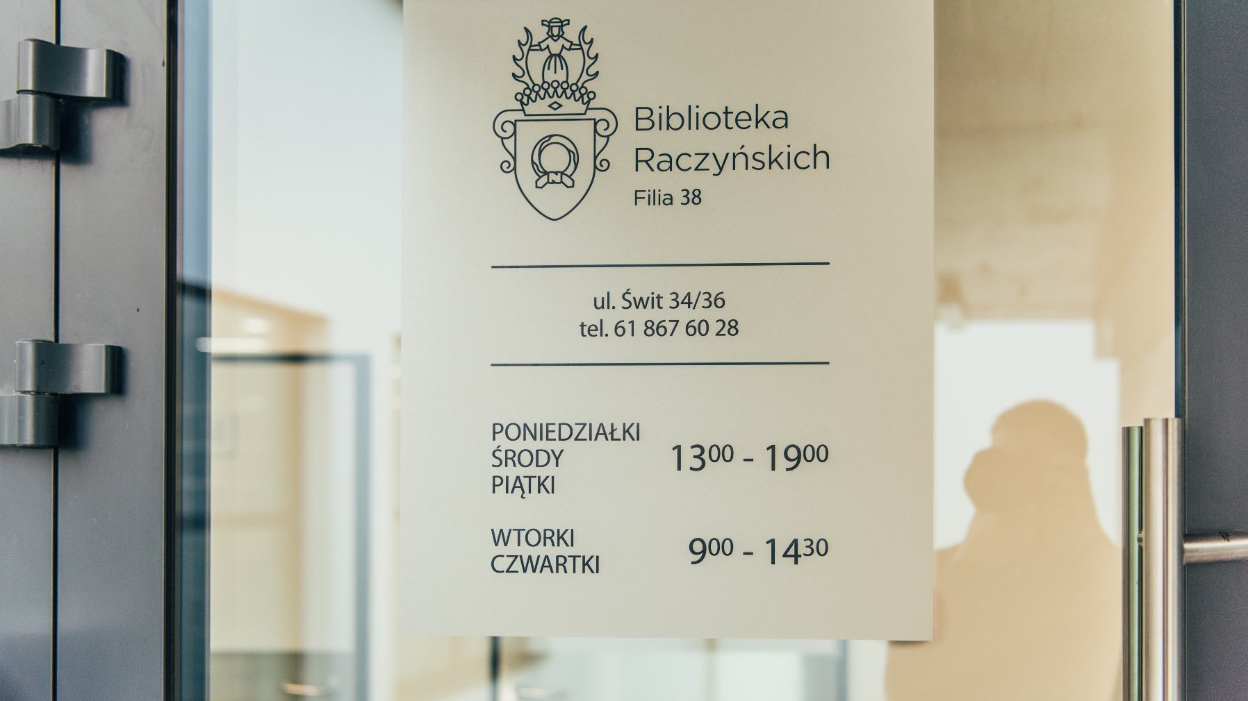 Na zdjęciu drzwi biblioteki z wypisanymi godzinami otwarcia