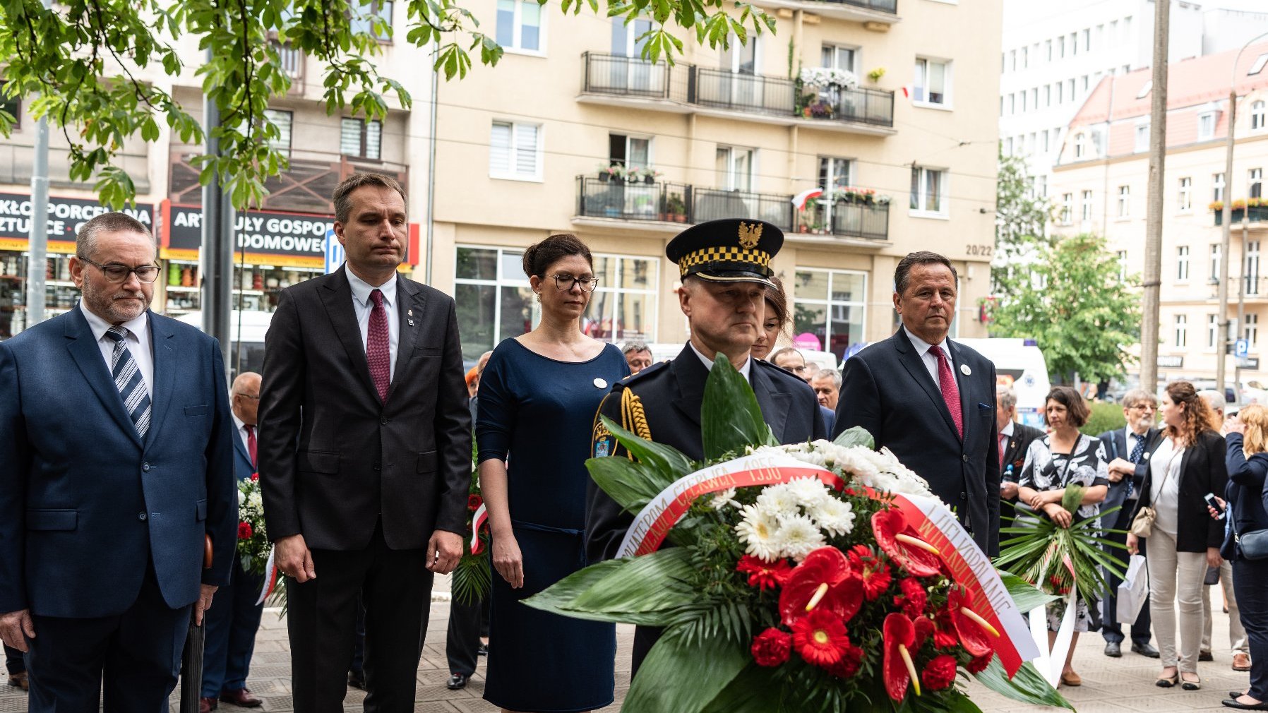 Na zdjęciu 5 osób składających kwiaty, na pierwszym planie strażnik miejski z wiązanką