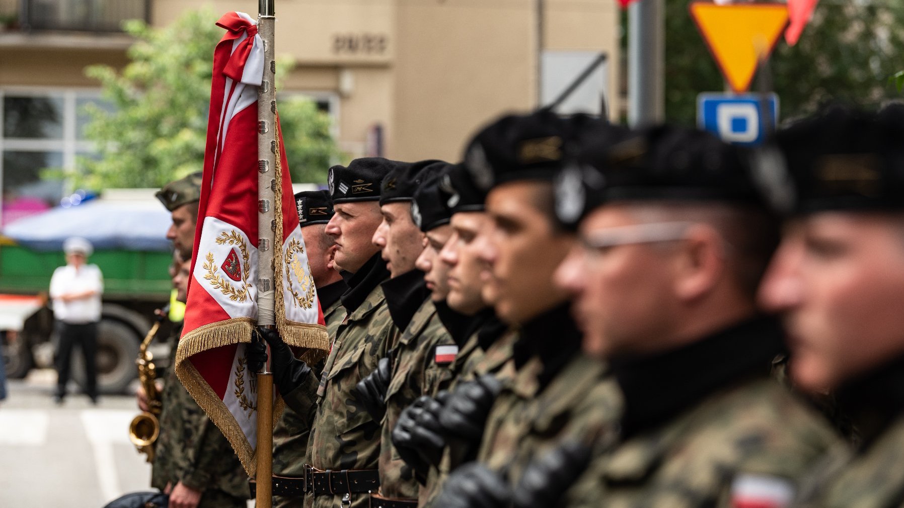 Na zdjęciu żołnierze stojący w szeregu, trzymający sztandar