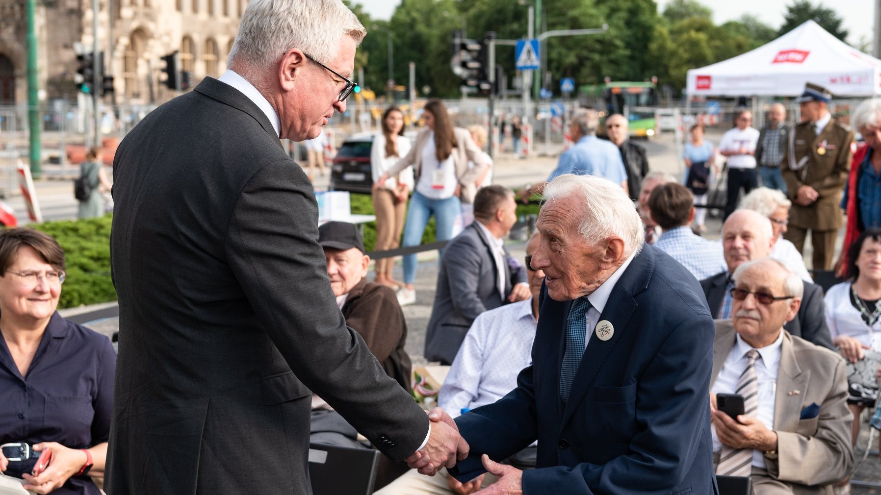 Na zdjęciu Jacek Jaśkowiak, prezydent Poznania, witający się ze starszym mężczyzną, Zenonem Wechmannem