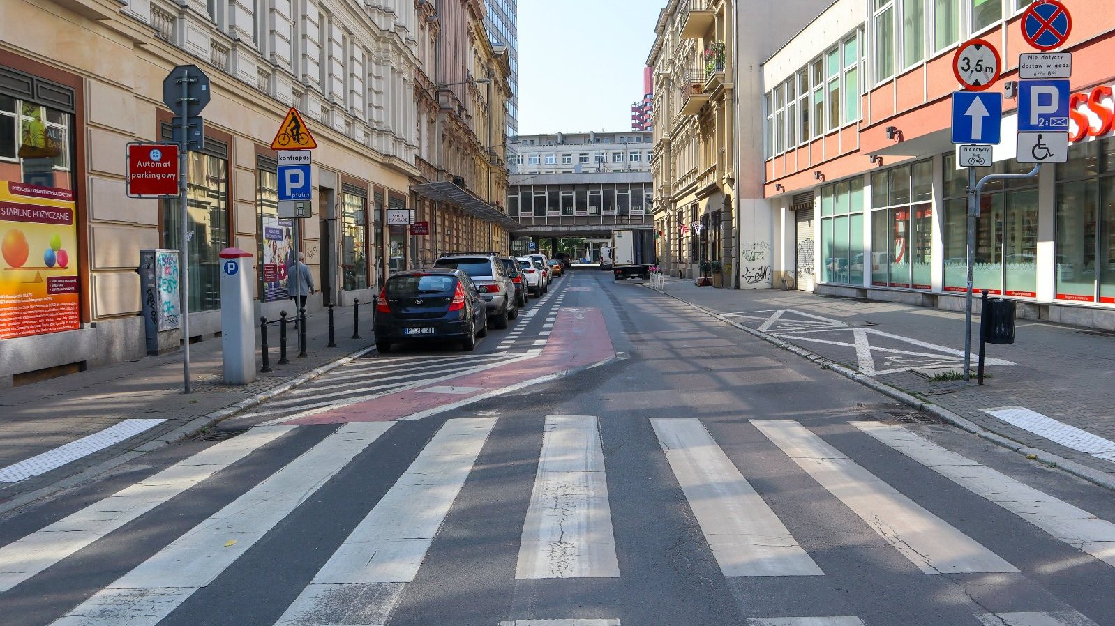 Na zdjeciu ulica w centrum miasta, na pierwszym planie przejście dla pieszych