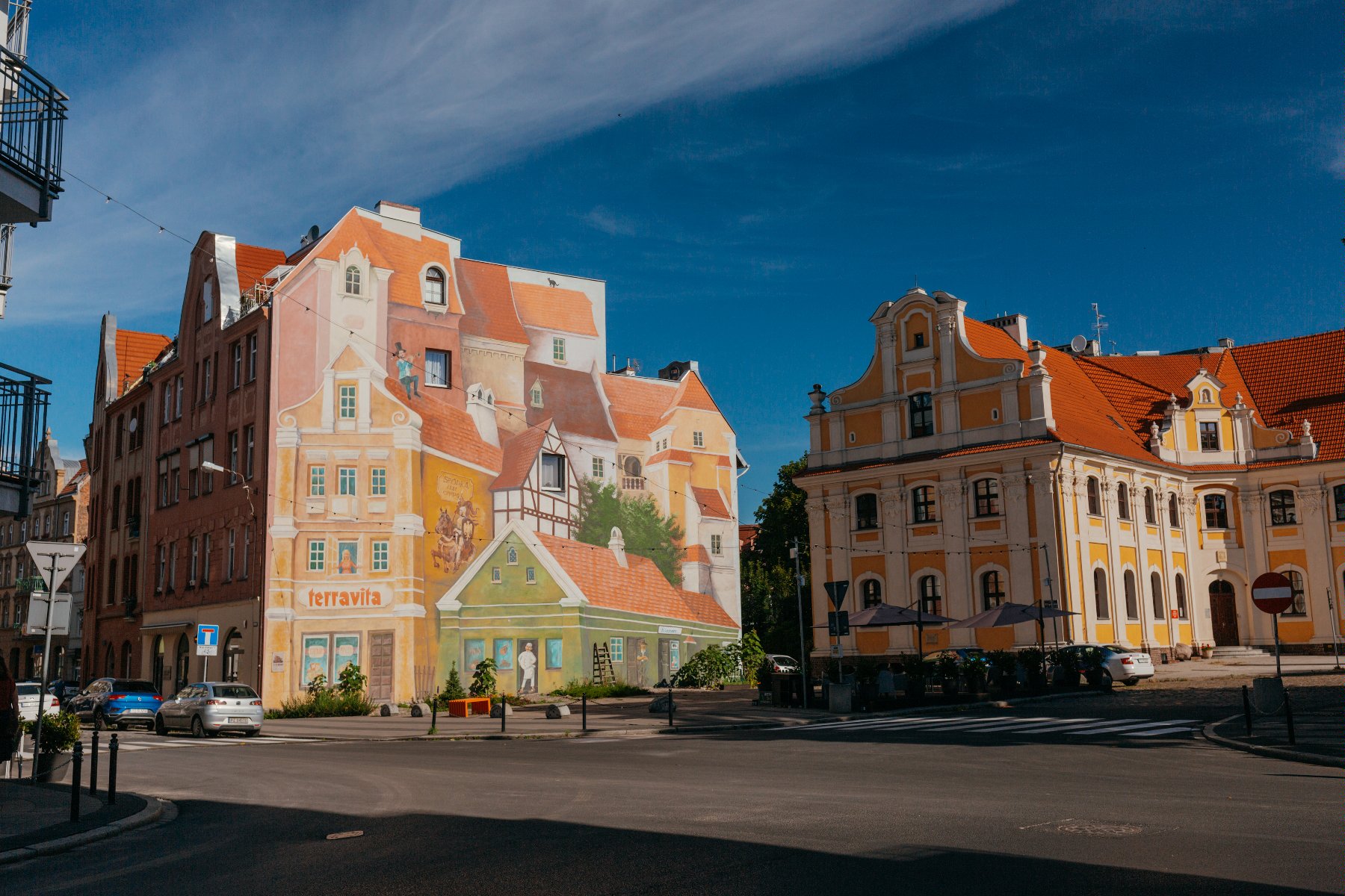 Zdjęcie przedstawia plac przed charakterystycznym śródeckim muralem, który widać na drugim planie. - grafika rozmowy