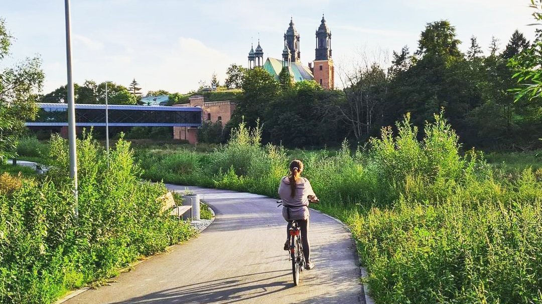 Rowerzystka na Wartostradzie koło Bramy Poznania i Cybiny. W tel widać katedrę