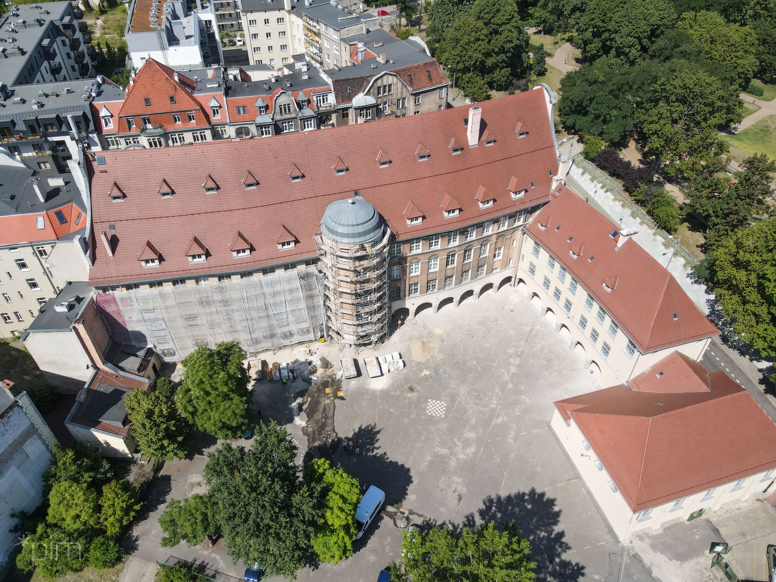 Zdjęcie pokazuje dziedziniec szkoły przy ul. Różanej. Po prawej stronie elewacja niższego budynku została już odnowiona. Teraz zasłonięta jest część po lewej od wieżyczki - grafika rozmowy