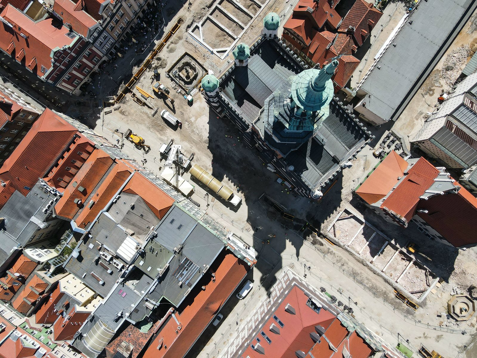 Zdjęcie przedstawia widok na Stary Rynek w Poznaniu z lotu ptaka. Na fotografii widoczen są dachy kamienic i sprzęt budowlany. - grafika rozmowy