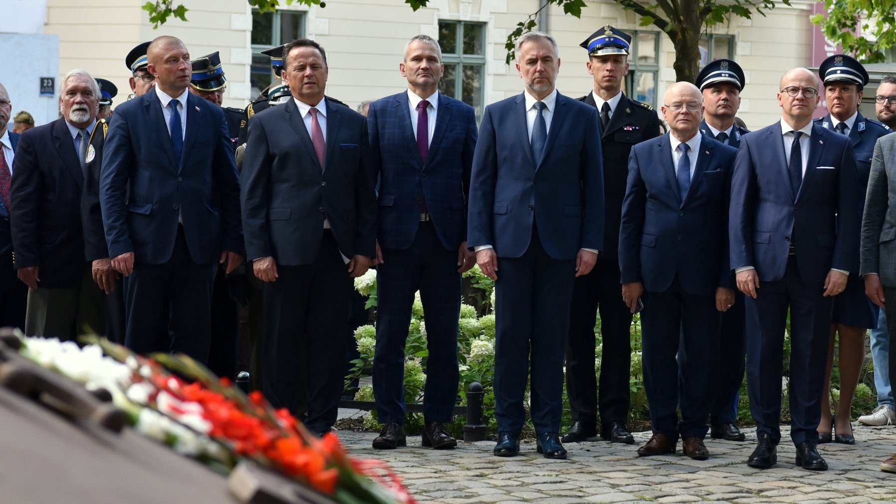 Na zdjęciu uczestnicy uroczystości stojący obok siebie, w pobliżu pomnika