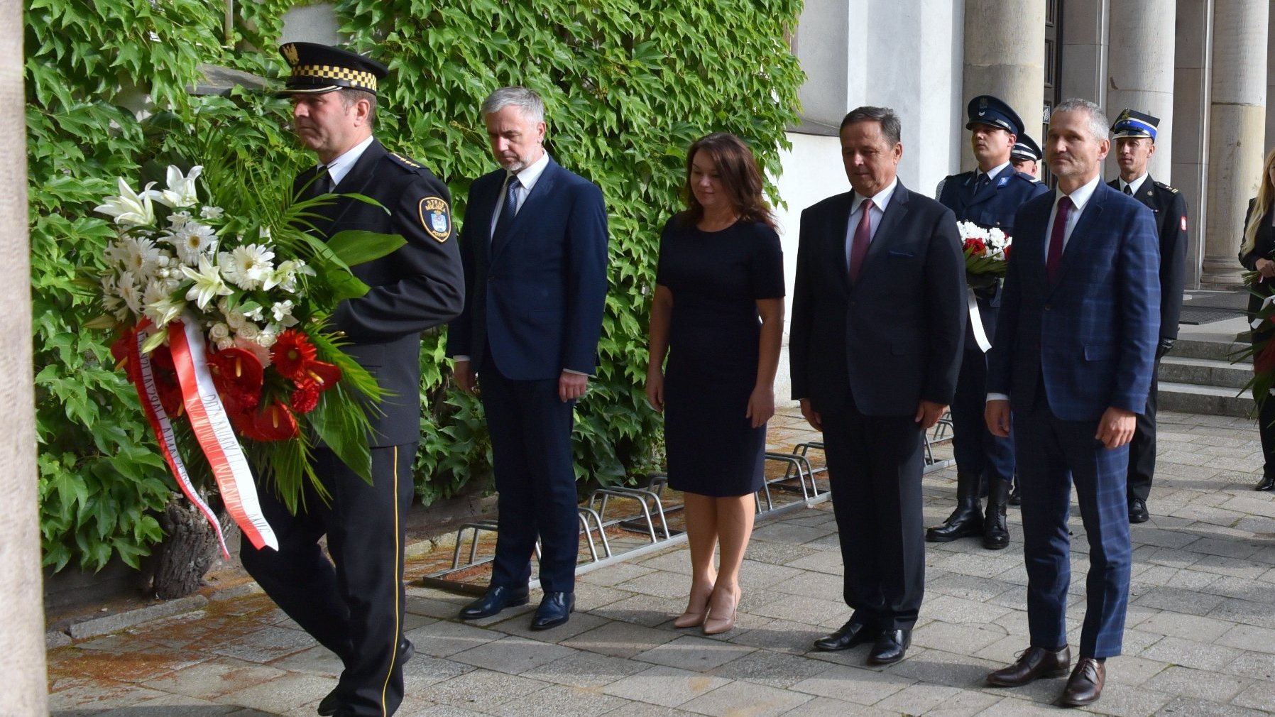 Na zdjęciu przedstawiciele samorządu i rządu składający wiązankę w krużgankach kościoła