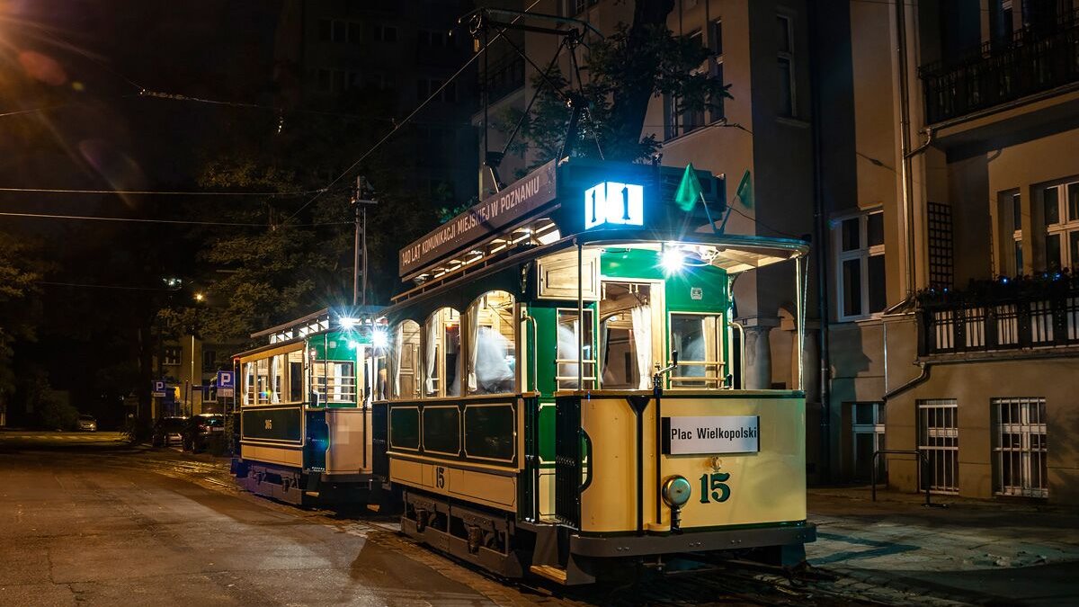 Na zdjęciu zabytkowy tramwaj stojący na torach, oświetlony lampami, po zmierzchu