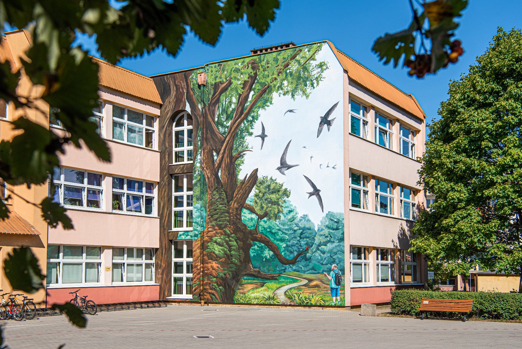 Galeria zdjęć przedstawiająca mural na szkole z różnej odległości oraz perspektywy - grafika rozmowy