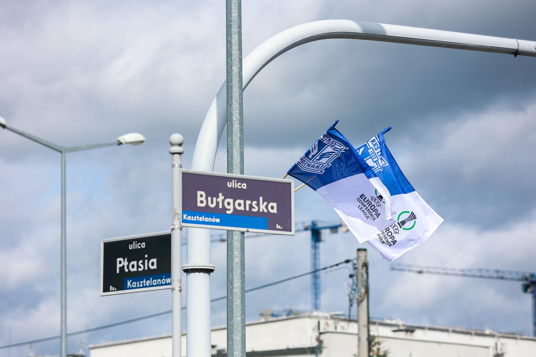 Niebiesko-białe flagi Lecha Poznań wiszące przy ulicach wokół stadionu miejskiego w Poznaniu - grafika rozmowy