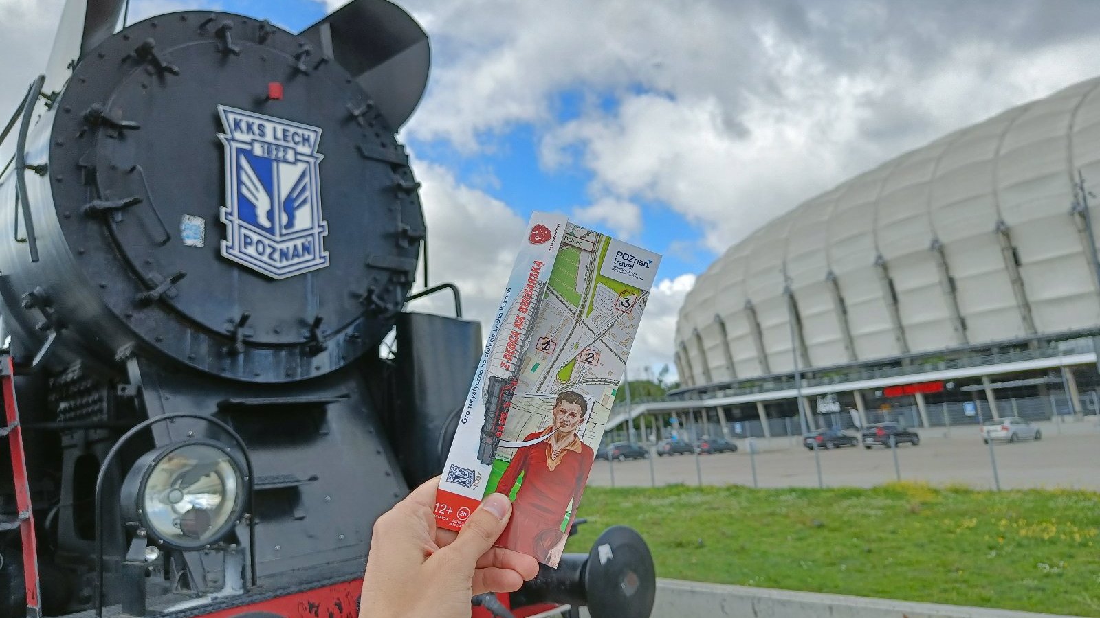 Na zdjęciu lokomotywa oraz stadion miejski, na pierwszym planie karta do gry