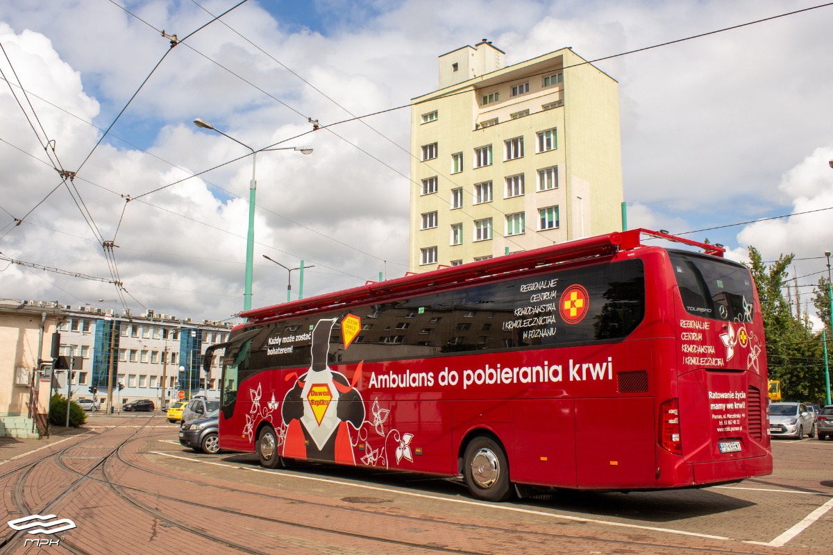 Na pierwszym planie widać czerowny autobus. W tle budynki. - grafika rozmowy