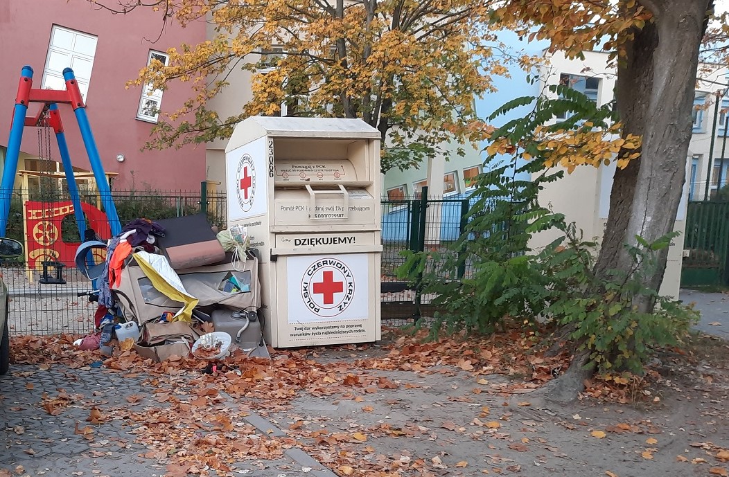 Na zdjęciu śmieci leżące przy kontenerze PCK na używaną odzież - grafika rozmowy