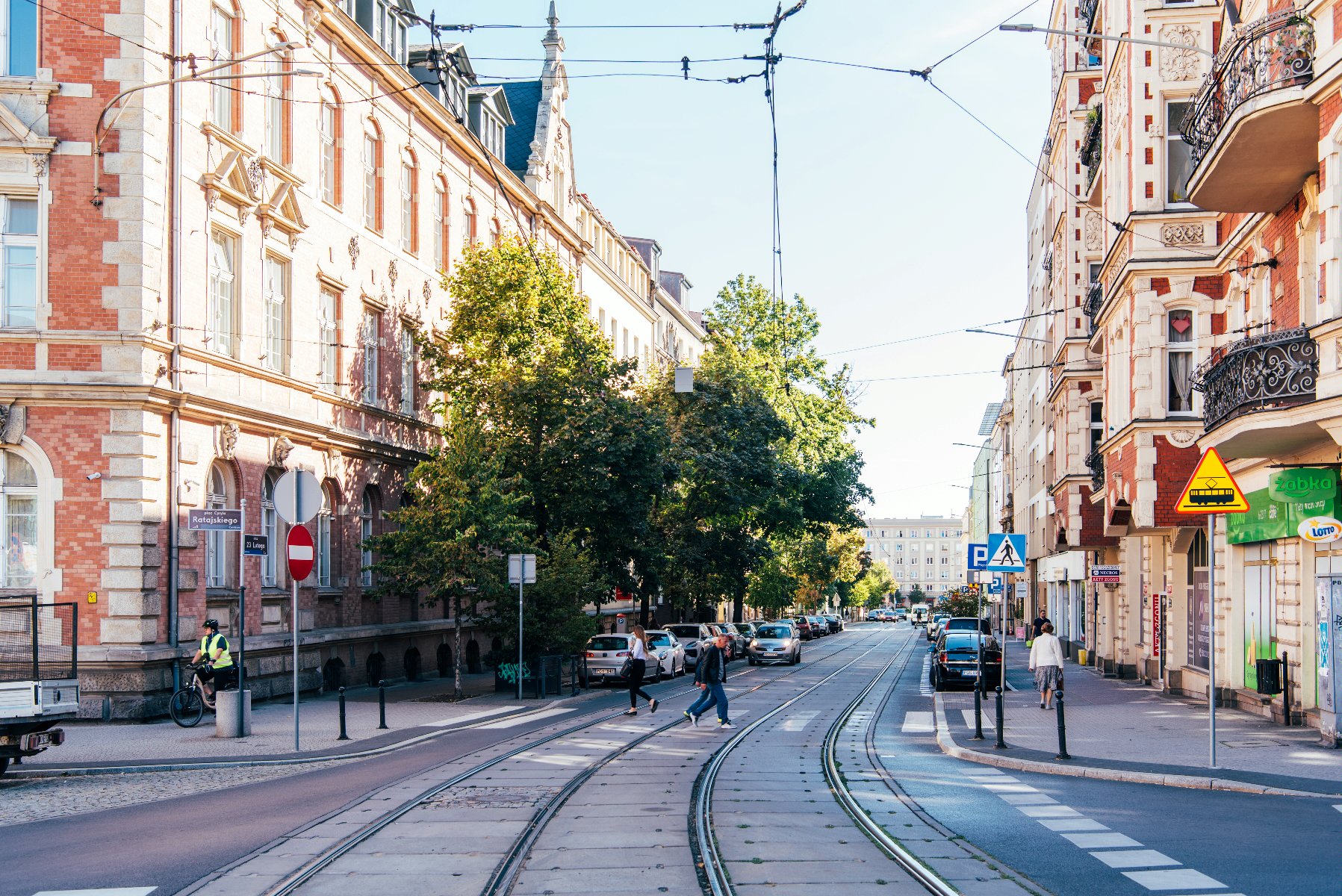 Na zdjęciu ulica 23 Lutego, w centrum torowisko, widać przechodniów i budynki - grafika rozmowy