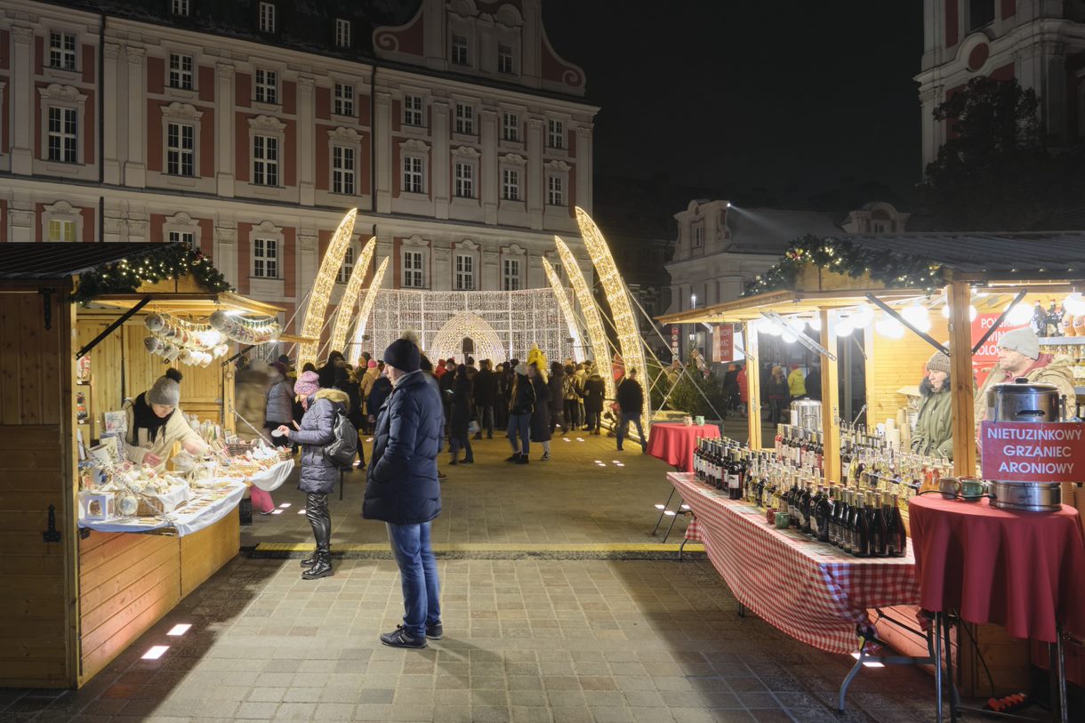 Na zdjęciu ludzi odwiedzający stoiska na jarmarku, w tle iluminacje - grafika rozmowy