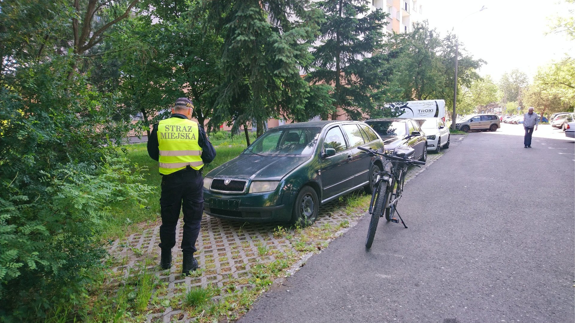 Na zdjęciu strażnik miejski przy porzuconym samochodzie