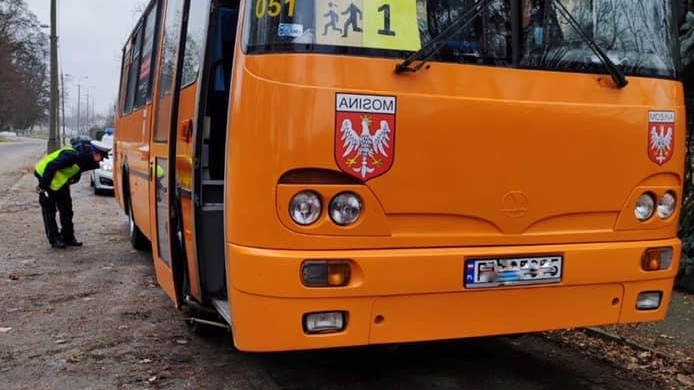 Na zdjęciu policjant przyglądający się tylnej oponie autobusu