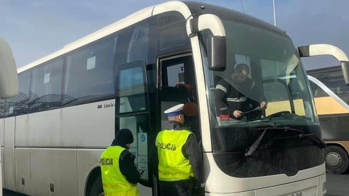 Na zdjęciu dwóch policjantów stojących przed autokarem