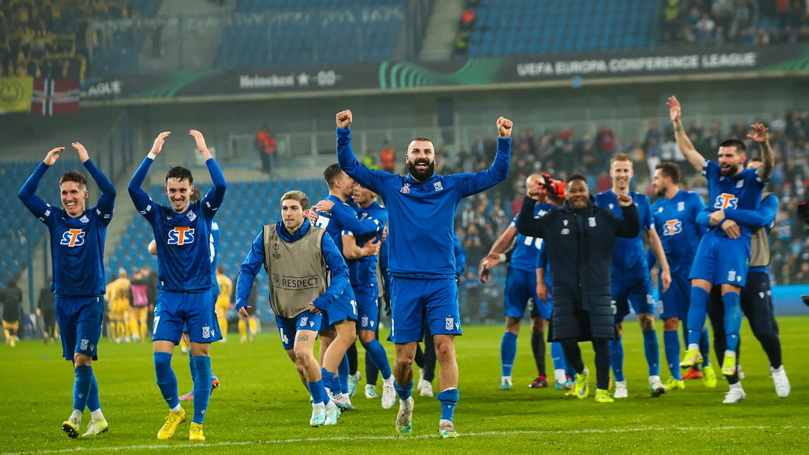 Zdjęcie przedstawia piłkarzy Lecha Poznań wznoszących ręce w geście zwycięstwa.