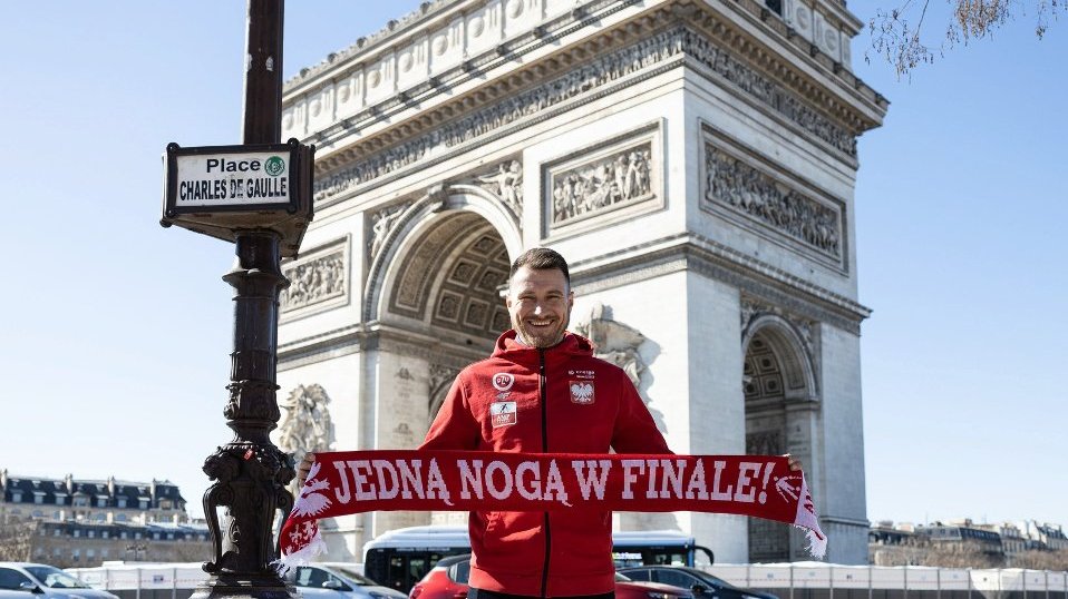 Marcin Oleksy pod Łukiem Triumfalnym w Paryżu z szalem z napisem "Jedną nogą w finale"