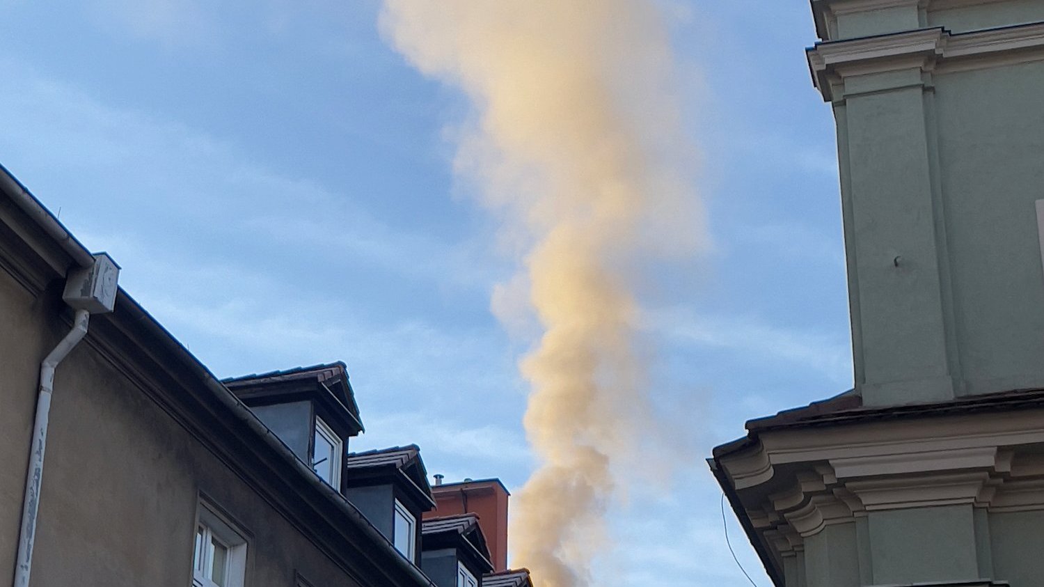 Zdjęcie poglądowe, dach domu z kominem, z którego unosi sie dym