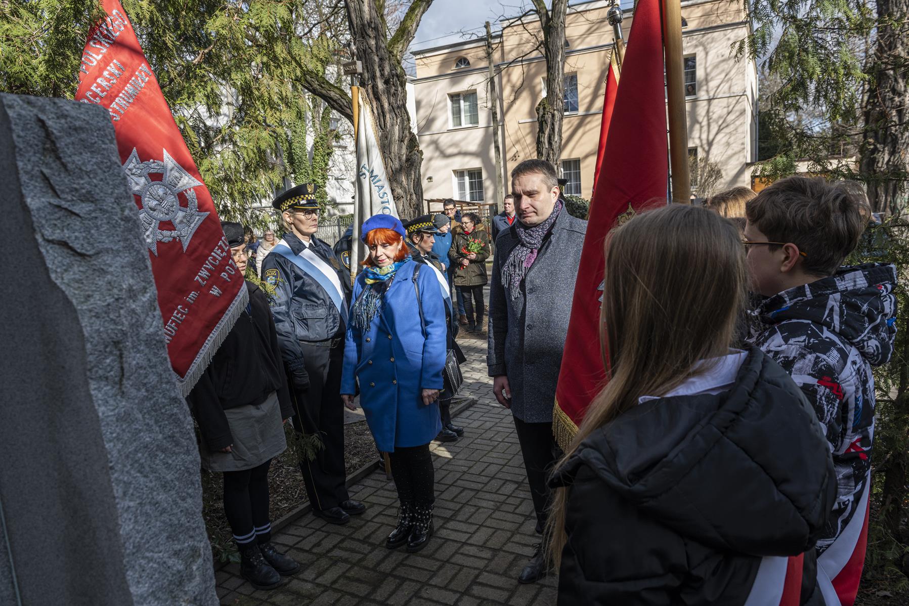 Na zdjęciu zastępca prezydenta Poznania składa kwiaty pod pomnikiem - grafika rozmowy