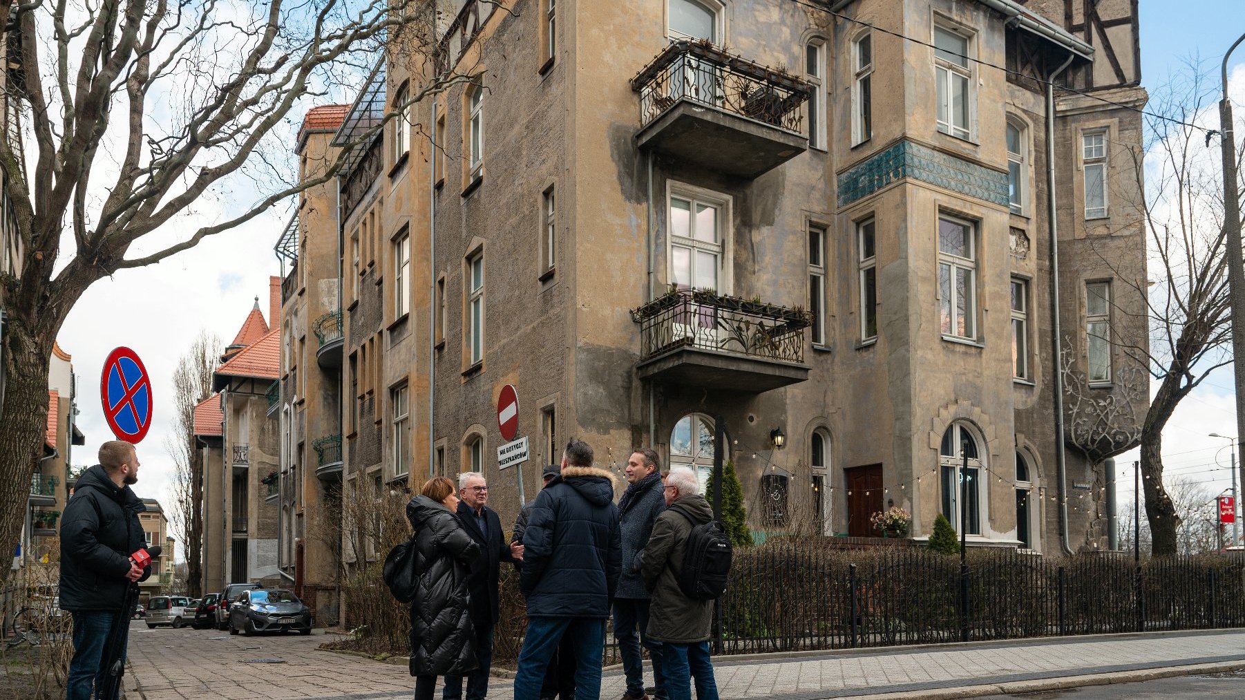 Na zdjęciu grupa osób przed secesyjną kamienicą