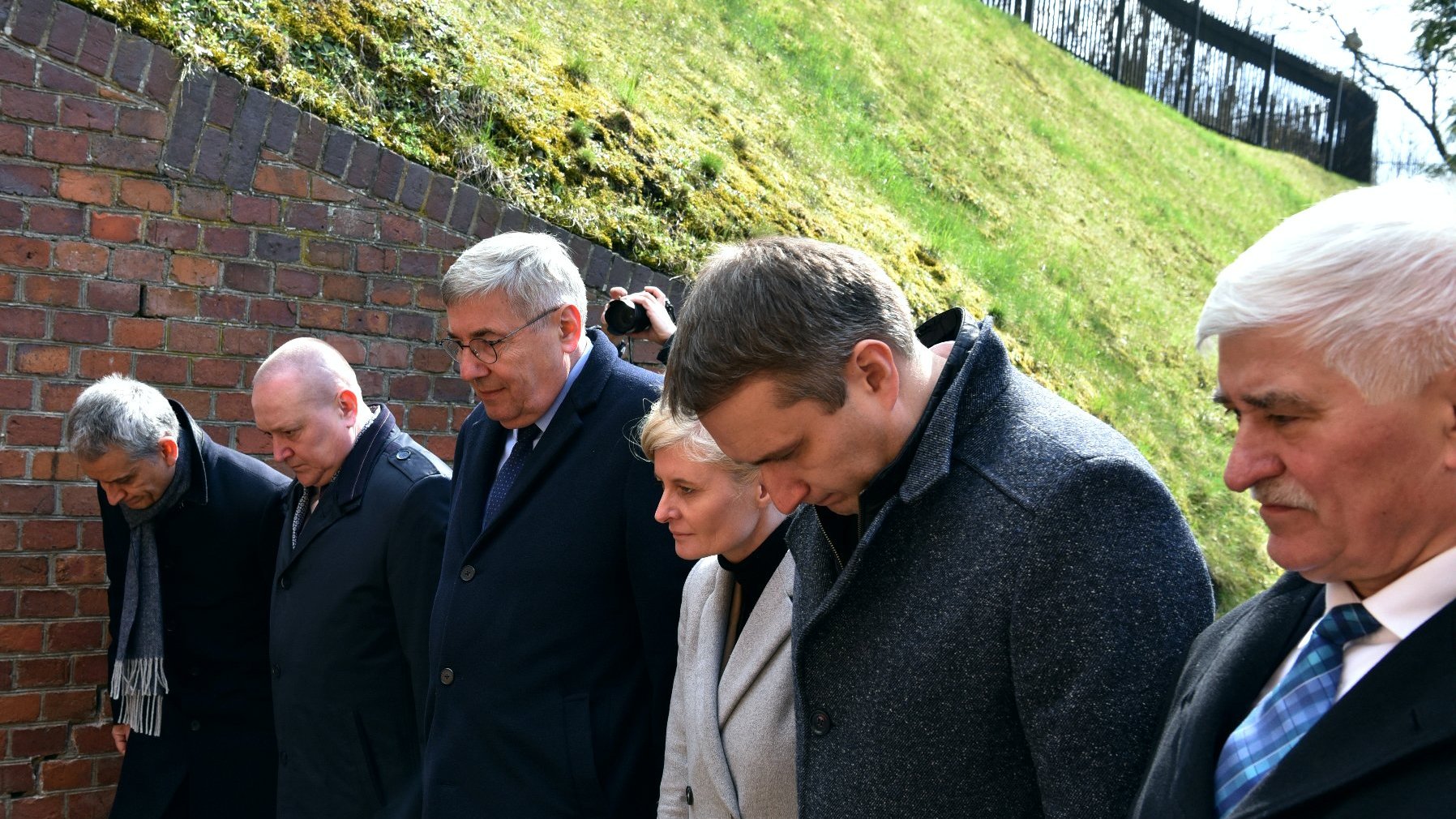 Na zdjęciu grupa osób pochylających się w ukłonie przed Ścianą Śmierci