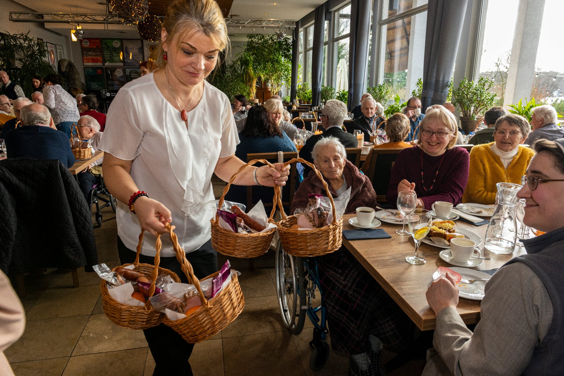 Na zdjęciu kobieta rozdająca koszyki seniorom - grafika rozmowy